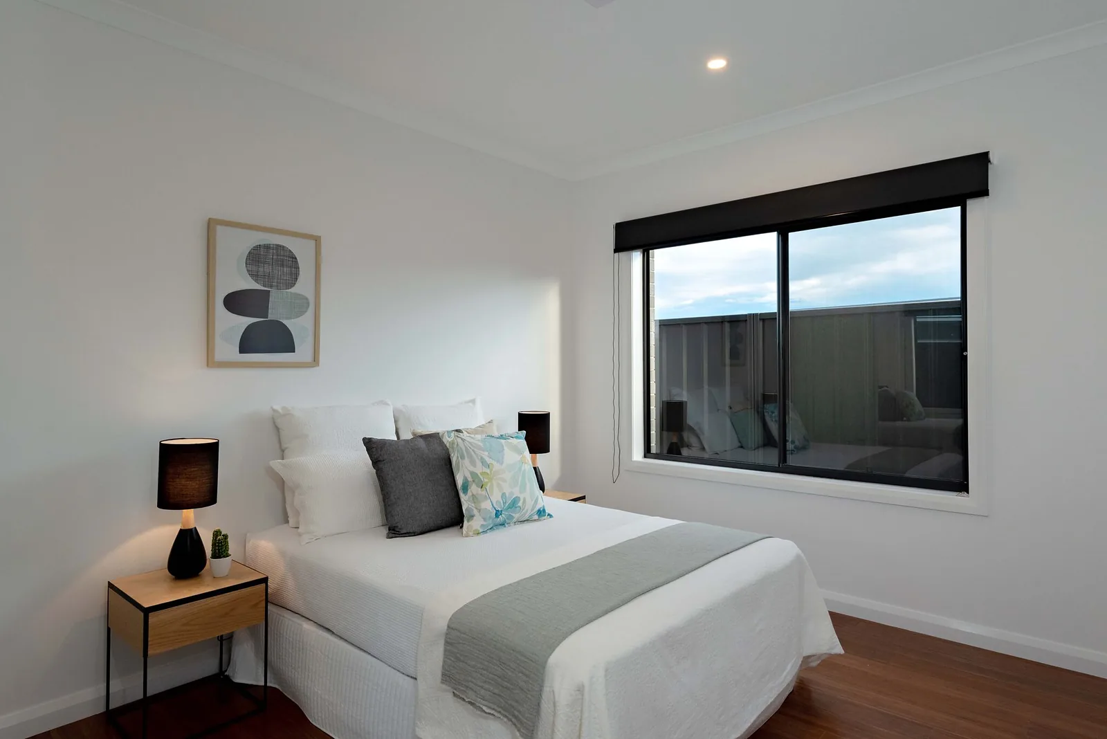 Guest bedroom with black framed window and timber floors