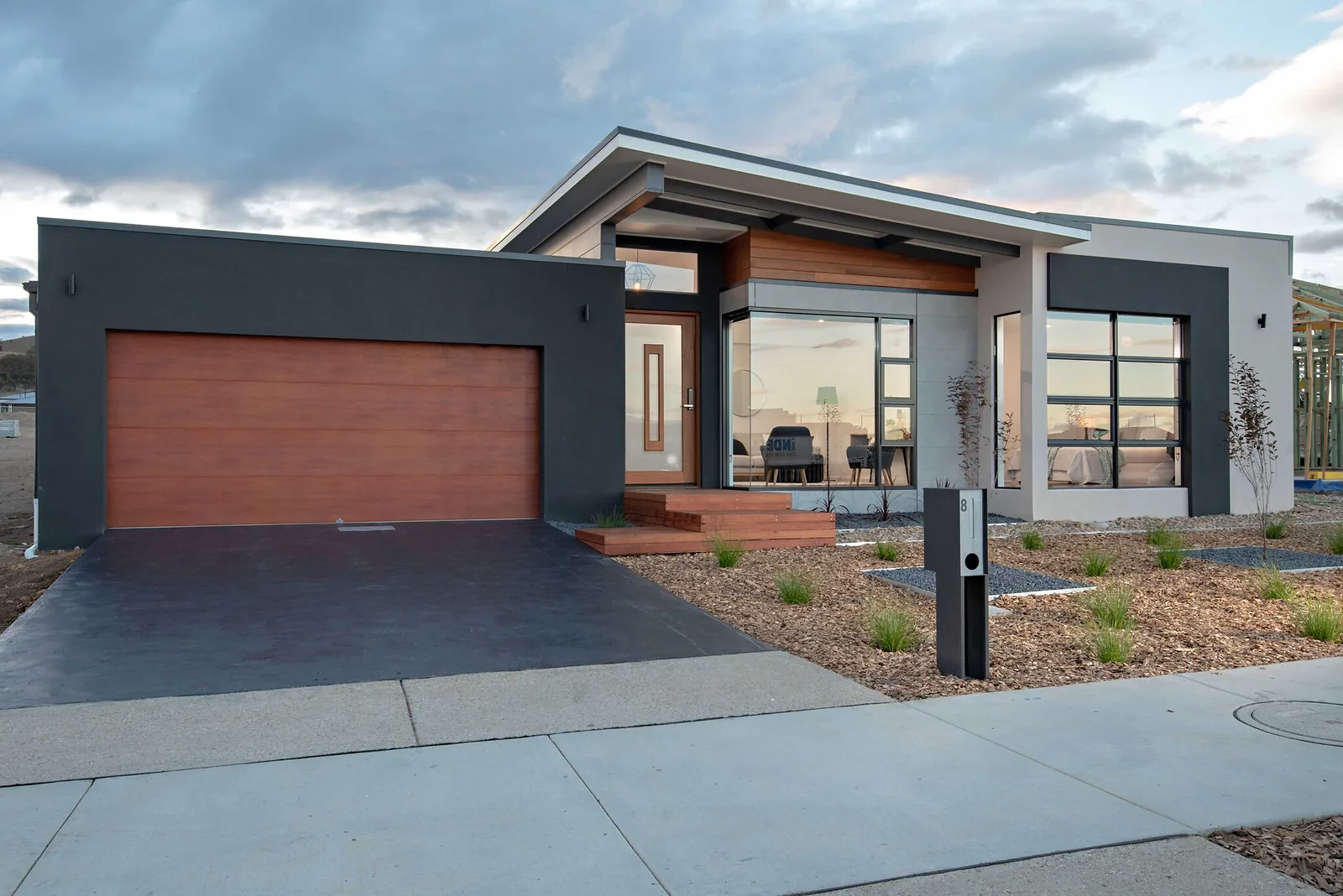Single storey new home at dusk with skillion roof and timber look garage door, Taylor ACT