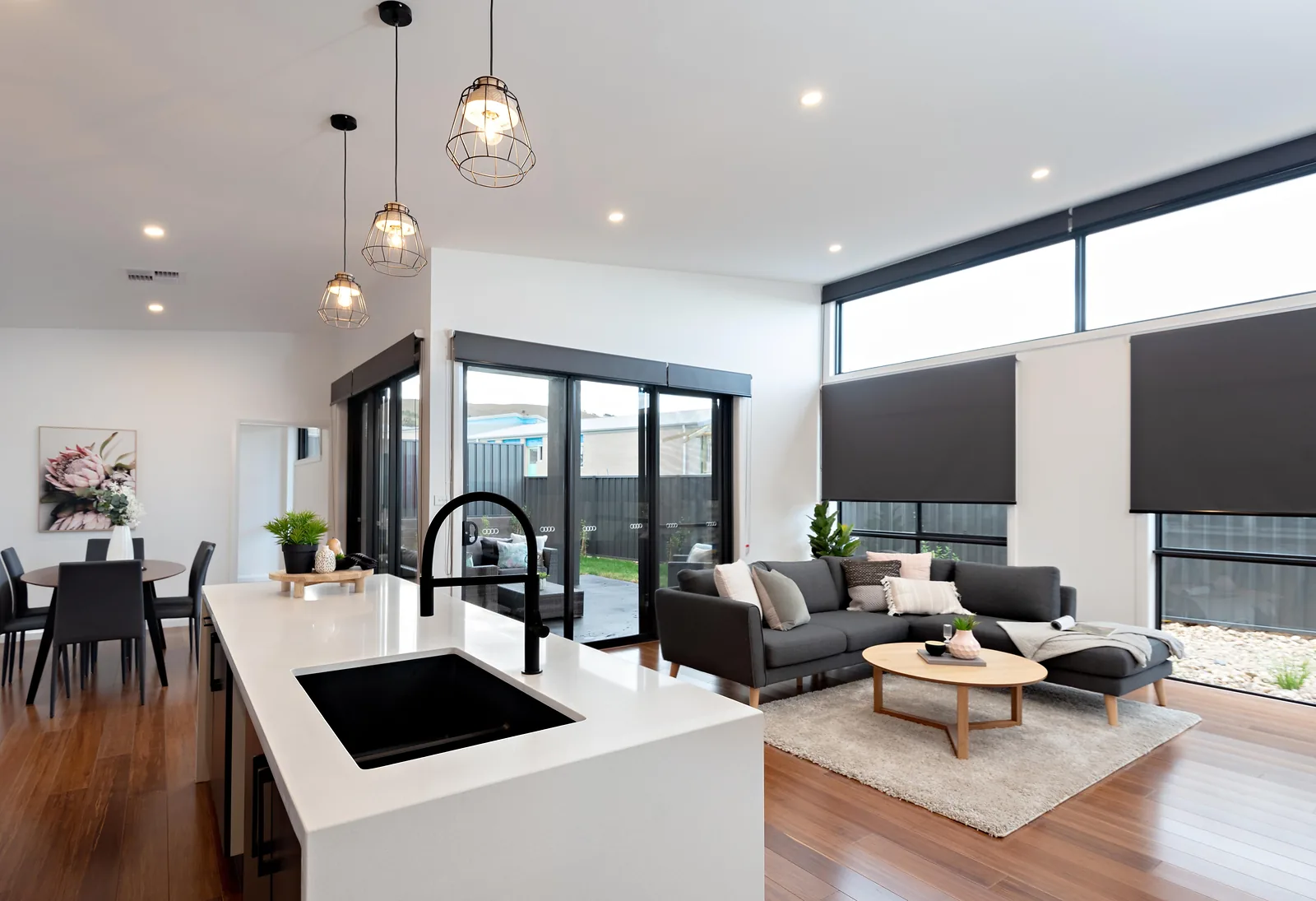 Kitchen island with black sink and living area under highlight windows