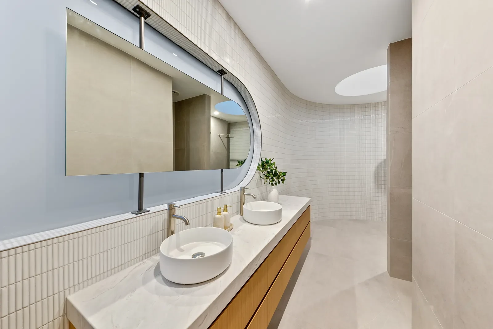 Ensuite with curved ribbon mirror, twin basins and finger tile splashback