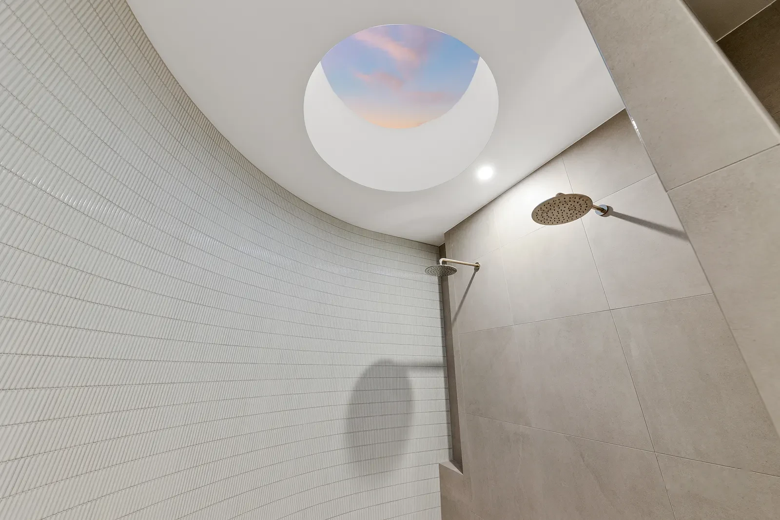 Walk in shower beneath an oval skylight open to the evening sky