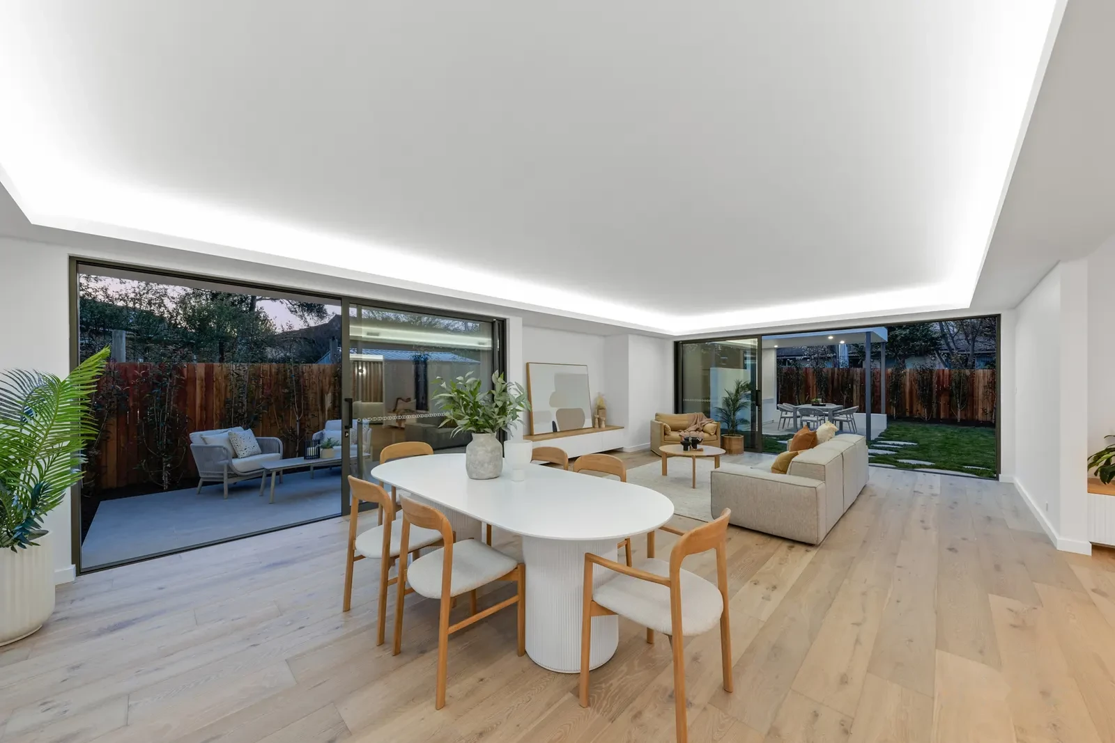 Dining area at dusk beneath a sculpted ceiling cove with concealed lighting