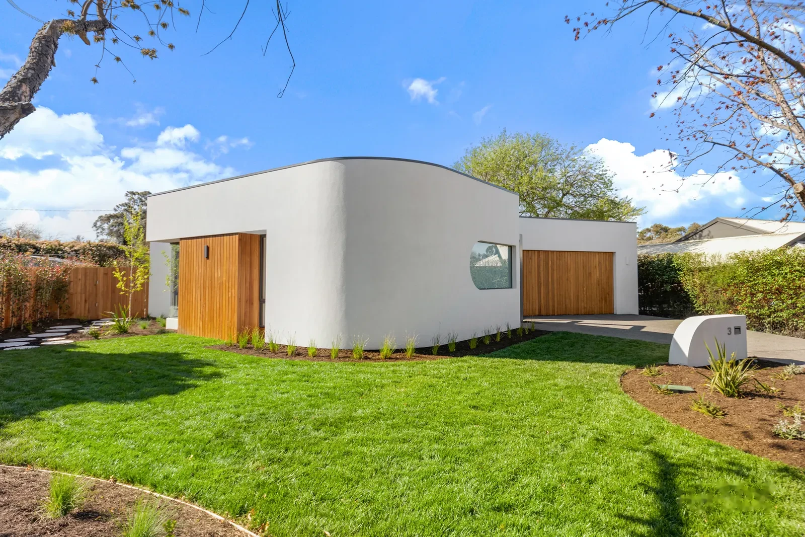 Architecturally designed home with curved white rendered facade and timber doors, Canberra